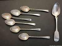 Top view of the 6 silver-plated spoons with twisted handles and shell-shaped bowls, alongside the sterling silver spoon.