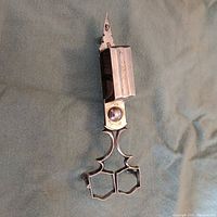 Full view of snuffer closed showing finger loops, hinge and wick box