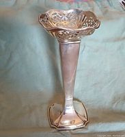 Photo showing the antique sterling silver vase upright with detailed pierced floral pattern at flared top and tapered square base.