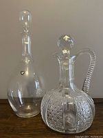 Photo showing both glass decanters side by side, highlighting the shape and condition, including original Orrefors sticker on the taller decanter.
