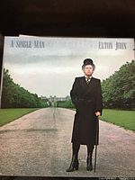 Elton John 'A Single Man' LP cover showing man in black coat and hat standing on a path, the album is in near mint condition with original insert in gatefold sleeve.