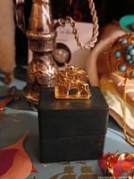 Charm displayed on black box, angled view showing front and side detail