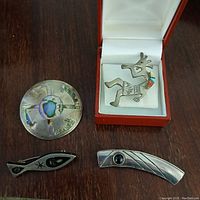 Top view of four vintage Mexican sterling silver brooches showing front designs and colors