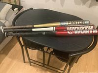 Three softball bats stacked on a black table showing branding and length.