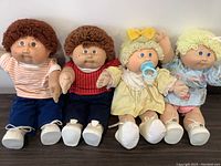 Front view of four Cabbage Patch Kids dolls including two twin boys and two twin girls with detailed clothing and shoes.