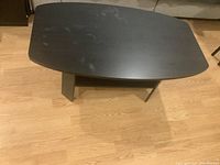 Top-down view of the small black coffee table showing the rectangular top with curved sides and light smudges.