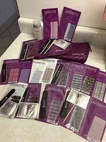 Photo showing multiple unopened Jamberry nail wrap packs in assorted patterns along with accessories and storage pouches arranged on countertop.