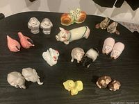 Top-down view showing all 11 sets of animal-themed salt and pepper shakers arranged on a black table surface.