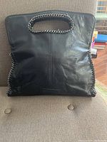 Front view of black leather purse with chain handle, showing the shape and condition