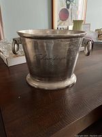 Front angled view of the silver-tone champagne bucket showing its handles and engraved 'Champagne' text.