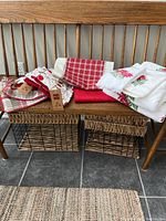 Overview of assorted Christmas-themed linens on a wooden bench showing folded runners, towels, and pillow covers with festive patterns.