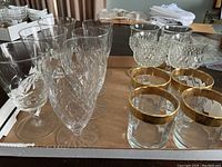 12 crystal glasses displayed on table showing four different styles including etched, cut, and gold-rimmed glasses.