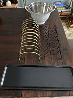 Metal plate racks, colander, and tray laid out on a table