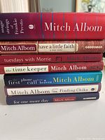Stack of seven hardcover Mitch Albom books showing spine titles and various colored dust jackets.