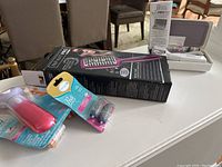 Photo showing all three items including the Infinity straightening brush box, Amope foot file, and Pearl nail buffer set on a white table.