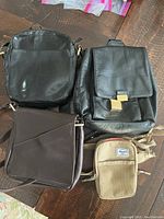 Lot of 4 purses; two black leather handbags, one brown leather crossbody, one small beige Herschel pouch
