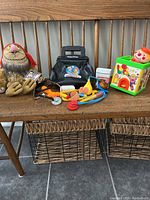 Photo showing all toys: Where the Wild Things Are plush, Fisher-Price medical kit with toys, and Jack-in-the-Box toy on wooden bench