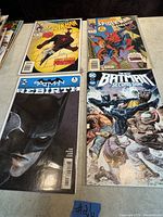 Photo showing four comics: two Spider-Man issues on top and two Batman issues below, placed on a light-colored surface.