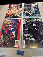 Photo showing four comic books: Superwoman, The Wretched/Punisher crossover, Marvel Spider-Man #1, and Catwoman #2 arranged on a wooden surface.