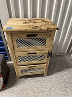 Full view of three-drawer wooden end table showing metal mesh drawer fronts and natural wood grain.