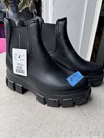 Side view of new with tags black chunky Chelsea boots with elastic sides and pull tabs.