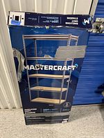 Boxed Mastercraft metal shelving unit in unopened original packaging, showing product photo and details on box.