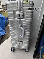 Front view of silver hard-shell suitcase with handle, combination locks, and four wheels.