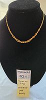 Front view of 14k yellow gold twisted chain necklace displayed on black bust