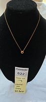 Full view of 14k gold necklace on display bust with pendant and attached tag