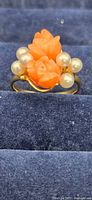 Front view of the 14k gold ring showing two carved coral rose shapes and pearls on a gold band.