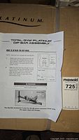 Instruction sheet titled 'Total Gym Platinum Dip Bar Assembly' taped to large box printed with Total Gym Platinum branding
