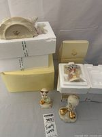 Porcelain teapot in styrofoam packaging with two Tweety Bird figurines placed beside box; one figurine white with gold accents, other hand painted