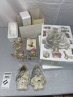 Overview of tree parts in box, figurines and wrapped ornaments on table