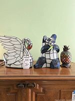 Photo showing swan, panda and pineapple Tiffany style figurines on a wooden surface