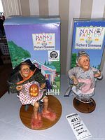Two Richard Simmons Nana's Family dolls with boxes. One dressed as a witch with a pumpkin, the other an elderly lady holding a bird and umbrella.