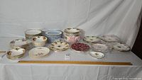 Table with multiple stacks of assorted china plates and bowls