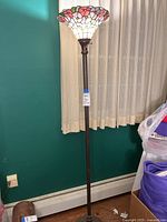 Full view of the lamp showing overall height, stained glass shade, and dark metal pole.