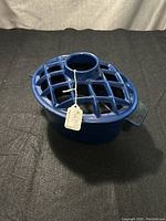 Top view shows lattice design lid with central hole and attached tag, glossy blue enamel cast iron steamer base with side handles.
