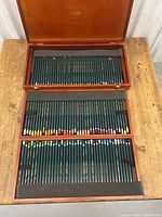 Open wooden case showing top tray of colored pencils