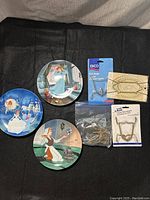 Three decorative Cinderella-themed plates with vivid illustrations plus assorted new and used wall hangers for display.