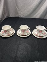 Three Queen Anne teacups each resting on their matching saucers, showing the floral design and condition.