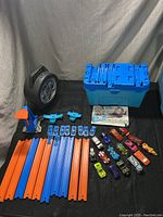 Layout of all items in the lot on a dark cloth background showing track pieces, cars, carrying case, and accessories