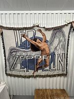 Front view of Led Zeppelin woven tapestry/banner with winged figure and band name design, tassel edges visible.
