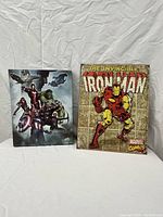 Two Marvel themed art pieces positioned side by side on a gray fabric background. Left is the Avengers printed canvas, right is the Ironman lithographed metal print.
