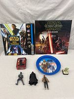 Full view of Star Wars toy lot including book, calendar, tin box, plate, and three action figures.