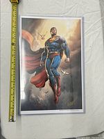 Full view of the Superman print in protective sleeve with measuring tape showing about 13 inches in height.