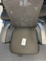 Front view of black mesh office chair with padded seat and armrests.