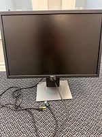 Front view of Dell monitor with cables on carpeted floor