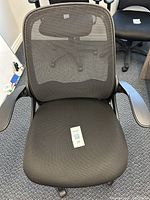 Front view of ergonomic black office chair showing mesh back, padded seat, and armrests.