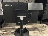 Rear view of the Lenovo ThinCentre Tiny-in-One monitor showing the Lenovo Tiny desktop PC attached to the back and various connection ports.